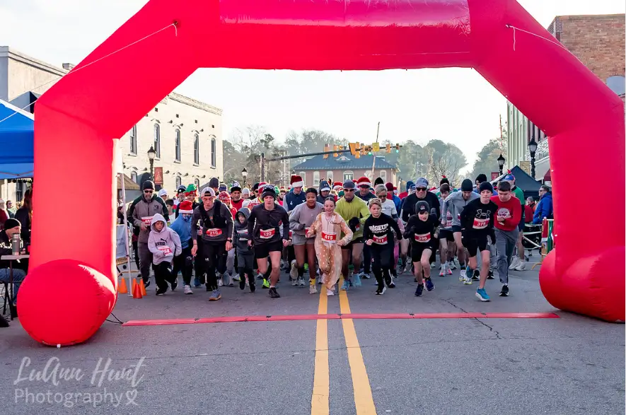Hundreds of runners taking off from the start line under a large red inflatable arch on downtown Aberdeen's main street