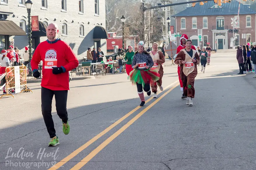 Runners in costume spread out along a straight downtown street lined with brick buildings